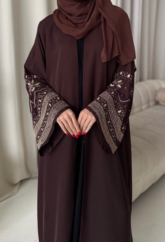 Brown abaya with intricate patterns on sleeves and neckline against a neutral background